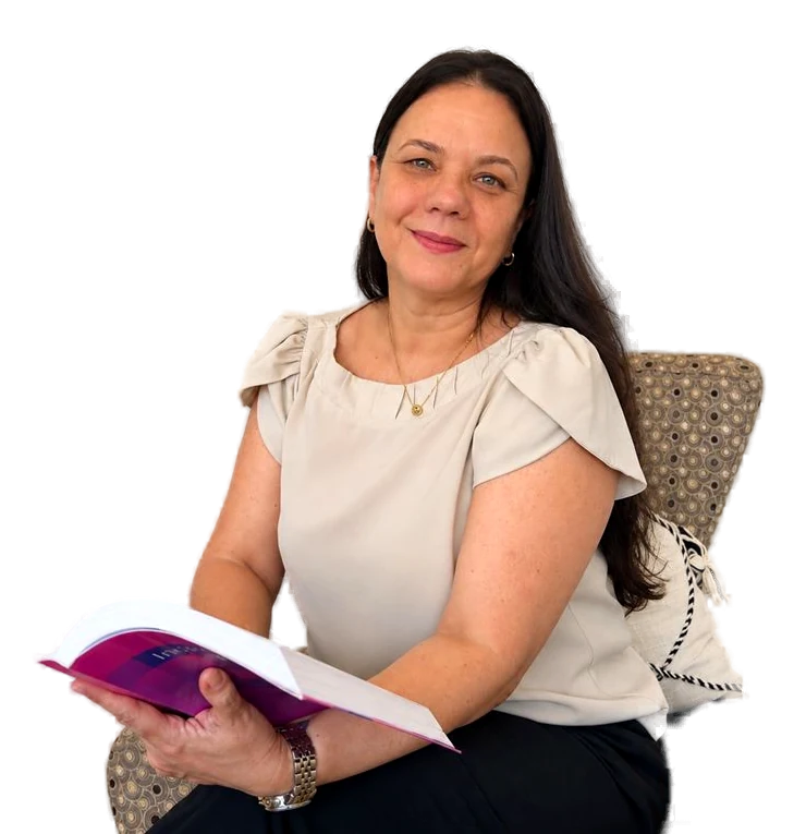 Mônica Ribeiro Oliveira sentada em poltrona com um livro aberto